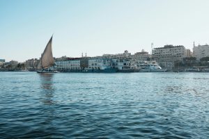 A picturesque view of a traditional sailboat on the Nile River near city waterfronts.