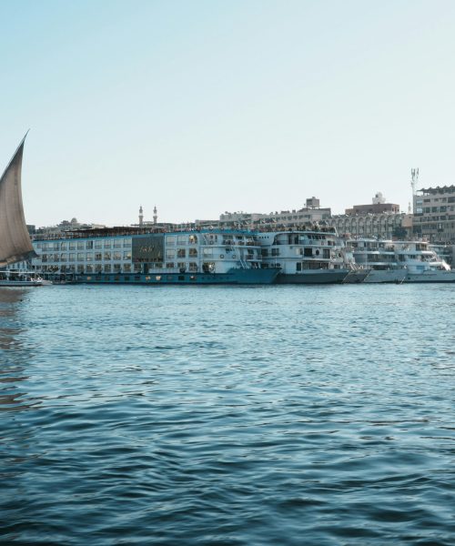 A picturesque view of a traditional sailboat on the Nile River near city waterfronts.