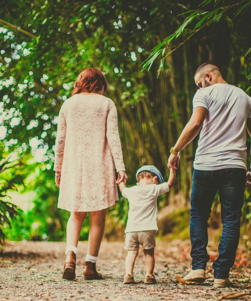 A family enjoys a leisurely walk in a green park, embodying joy and togetherness.