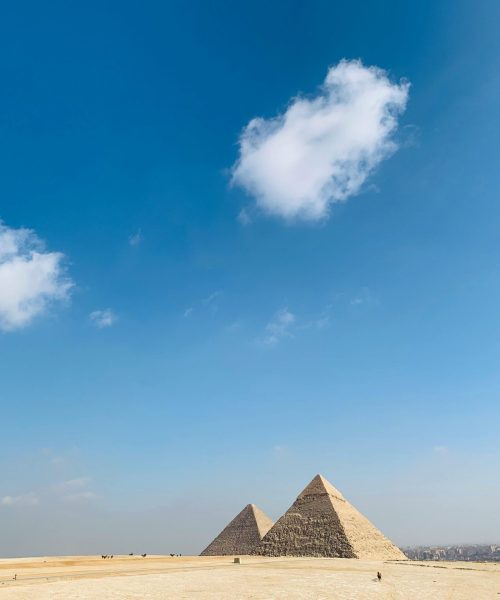 The historic Pyramids of Giza framed by a vast desert and blue sky, perfect for travel and tourism themes.