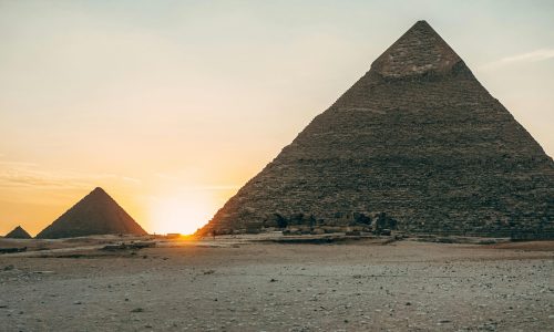 Dramatic sunset view of the iconic Giza Pyramids in Egypt, highlighting their ancient architecture.