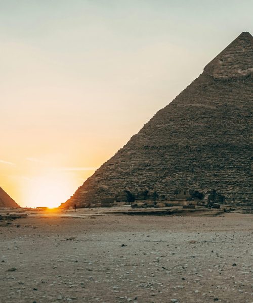 Dramatic sunset view of the iconic Giza Pyramids in Egypt, highlighting their ancient architecture.